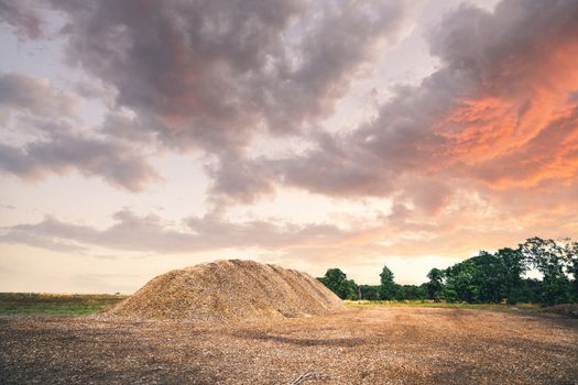 Mulch pile in the summer sunset in a rural landscape with dramatic sky