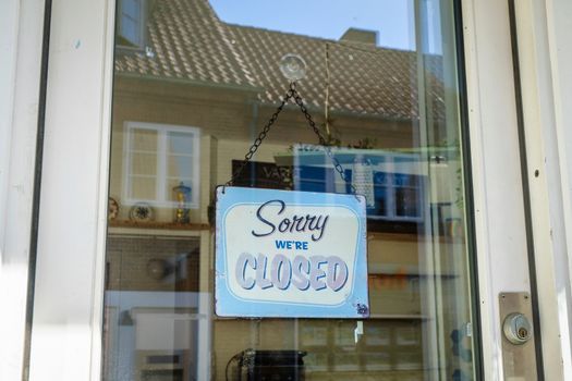Closed sign hanging in a store window on a city street with a retro look
