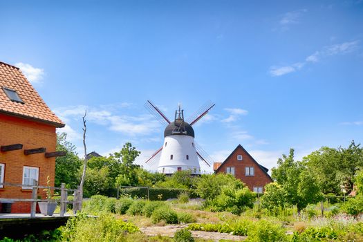 Old mill in a green garden in the summertime under a blue sky