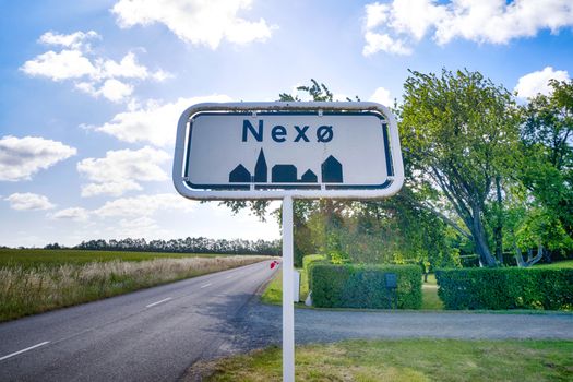 City sign of Nexø city on the danish island of Bornholm in the summer under a blue sky