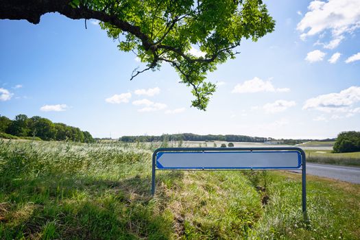 Road sign with an arrow in idyllic nature under a green tree in the summer