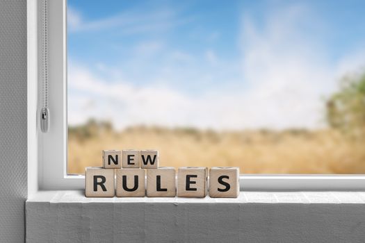 New rules sign in a window with a view to fields under a blue sky