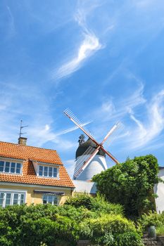 Idyllic mill in a small town under a blue sky with a green garden in the front