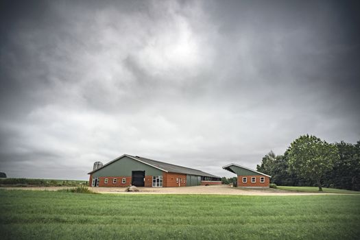 Farm under a cloudy sky with green fields waiting for the rain