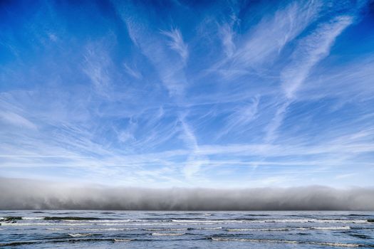 Cloudy weather over the ocean coming towards the shore under a blue sky