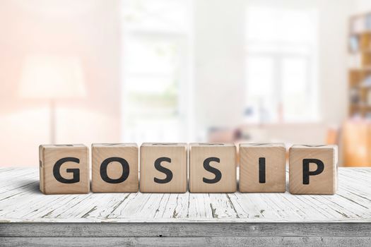 Gossip text sign in a bright living room on a white painted wooden desk