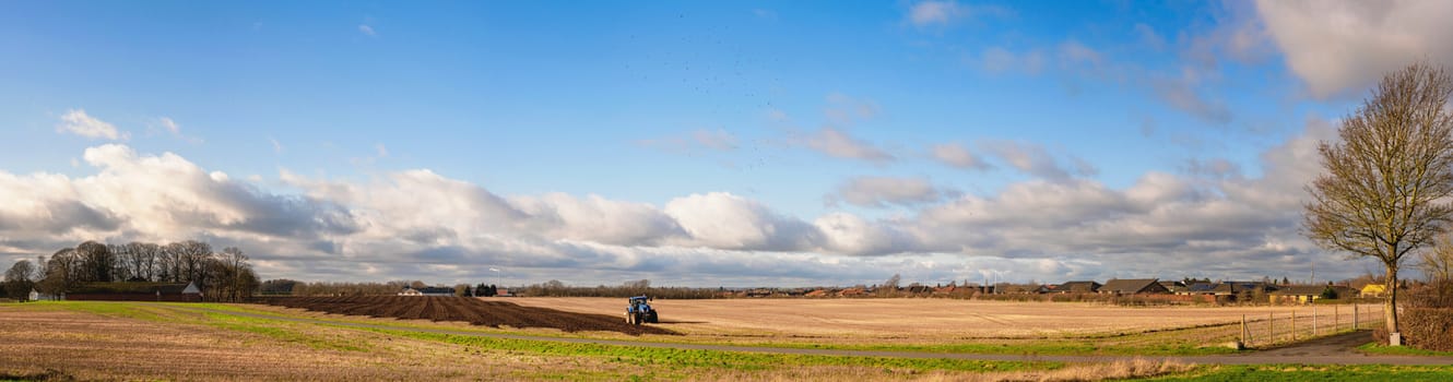 Tractor in a rural panorama landscape cultivating the soil on a field in the early spring