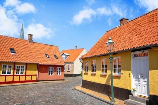 Street with yellow buildings and cooblestone on the road under a blue sky