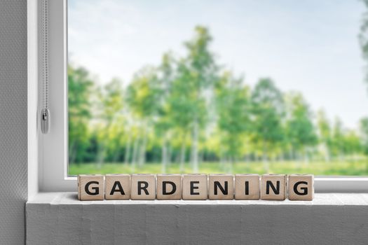 View to a garden in the spring with a gardening sign in a window sill