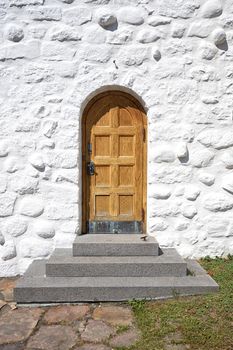 Wooden door with a stairway on an old building with white brick facade