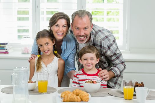 Portrait of smiling family having breakfast in the kitchen at home