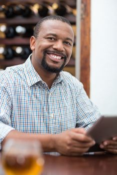 Handsome man smiling while using digital tablet in the restaurant