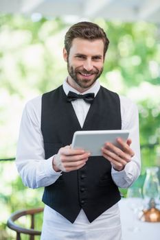 Portrait of male waiter holding digital tablet in restaurant