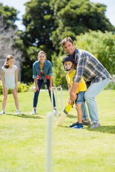 Happy family playing cricket together in backyard