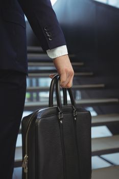 Low section of businessman holding briefcase