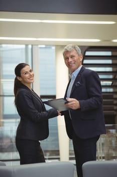 Portrait of business executives standing while holding a clipboard