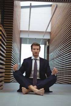 Businessman performing yoga in the corridor at office