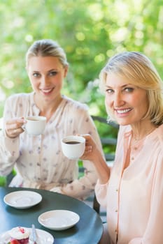 Portrait of smiling friends enjoying coffee together at restaurant