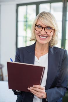 Portrait of businesswoman writing on diary in a restaurant