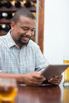 Happy man using digital tablet while sitting in the restaurant
