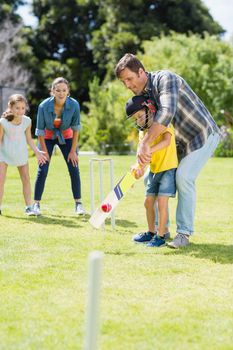 Happy family playing cricket together in backyard