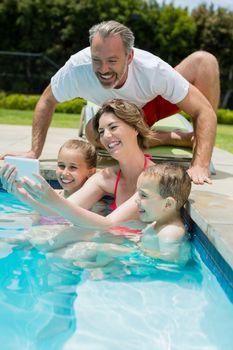 Woman taking selfie with family in swimming pool