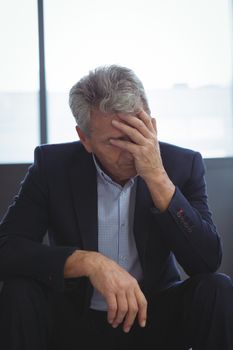 Depressed businessman sitting with hand on head at office