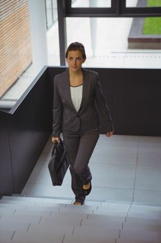 Businesswoman with briefcase climbing stairs at office