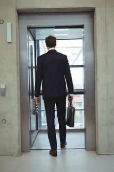 Rear view of businessman walking into an elevator at office