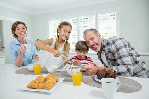 Portrait of smiling family having breakfast in the kitchen at home