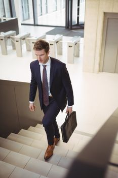 Businessman with briefcase climbing stairs at office