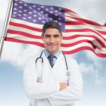 Smiling male doctor with arms crossed in hospital against composite image of low angle view of american flag