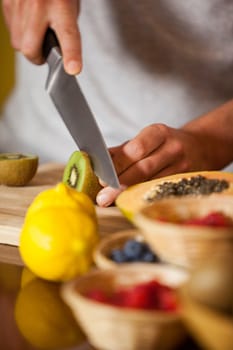 Mid-section of male staff cutting kiwifruit at organic section in supermarket