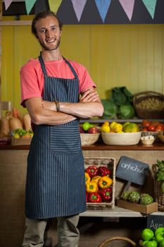 Portrait of male staff standing with arms crossed in organic section of supermarket