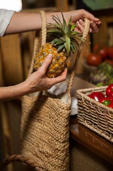 Woman buying pineapple at organic section in supermarket