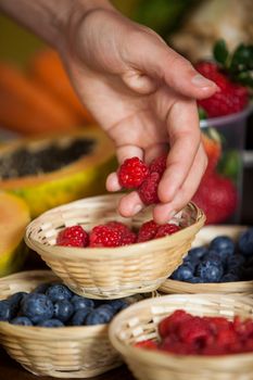 Hand of male staff holding raspberries in supermarket