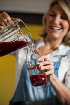 Female staff pouring juice in a bottle at health grocery shop