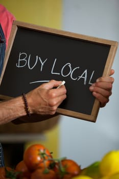 Mid section of male staff writing on slate board in organic section of supermarket