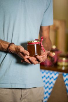 Mid-section of man holding a jar of jam in market