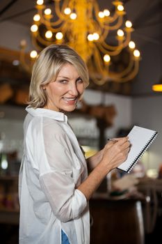 Portrait of female costumer maintain record in notepad at supermarket