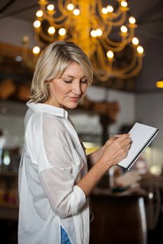 Female costumer maintain record in notepad at supermarket