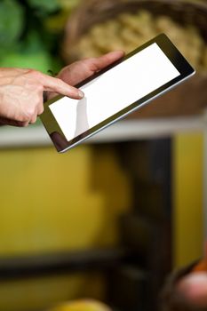 Hands of male staff using digital tablet in supermarket