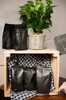 Coffee bags and pot plant on wooden table in coffee shop