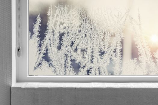 Frosty window seen from the inside with a white windowsill in the winter