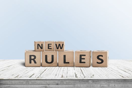 New rules sign made of wood on a desk in a room with a blue background