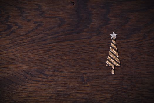 Golden Christmas tree with glitter on a wooden background in brown colors in the Xmas holidays