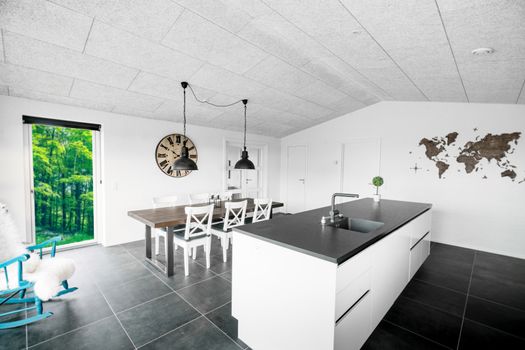 Large kitchen environment with a dinner table and a view to green nature