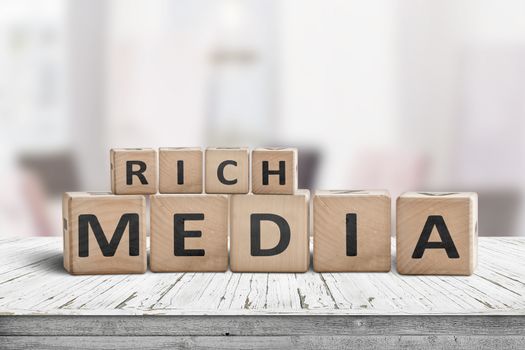 Rich media word sign on a wooden desk in a room in daylight