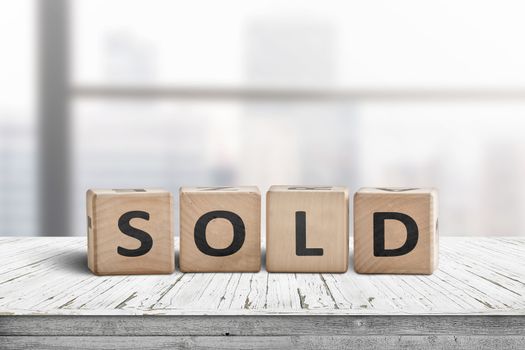 Sold sign on a wooden table with a bright windows in the background