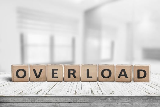 Sign with the word overload in a bright office environment on a wooden table